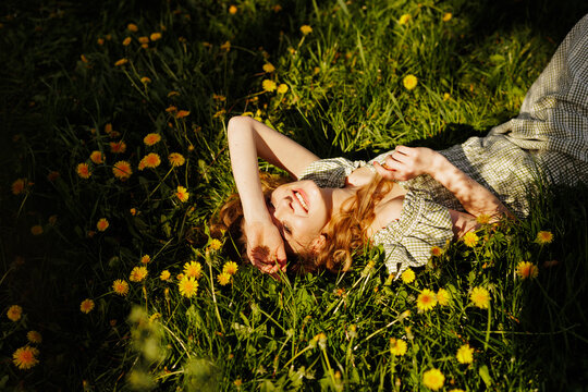 Young Woman Relaxing in a Field of Dandelions Under the Sun