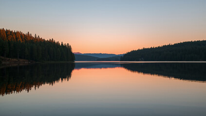 Fototapeta premium 夕焼けに染まる森が湖面に映る穏やかな山の風景写真