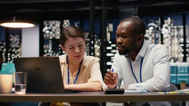Multiethnic coworkers collaborating in a corporate office, working late to complete project tasks. Colleagues engage in brainstorming, research and data analysis while refining business strategy.