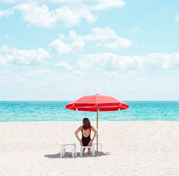 woman under beach umbrella chair miami florida