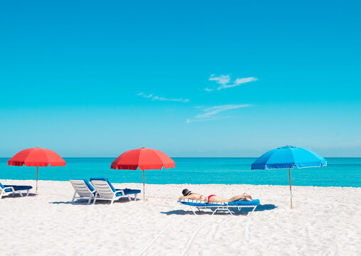 bikini woman on beach chair with colorful umbrellas in miami florida