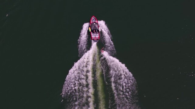 "Top-down drone tracking shot of a speedboat pulling a wakeboarder across Lucky Peak Reservoir, Idaho. Dynamic aerial view of high-speed watersports action with a powerful wake trail."
