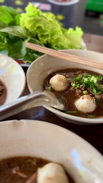 Close up of traditional Thai boat noodles with meatballs and rich broth