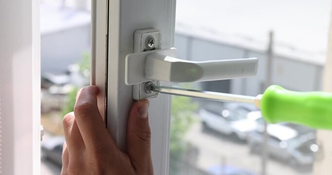 Worker with screwdriver installing window handle indoors, closeup