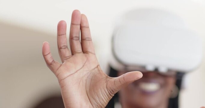 Adult African American woman making pinch, open and rotate gestures via white VR headset at home