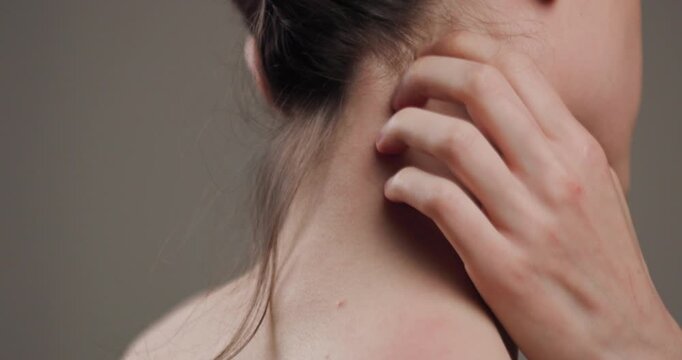 Close-up view of a woman scratching her neck, showing details of skin and fingers