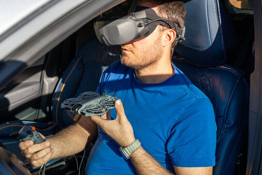 Man in car using VR headset, holding remote controller and mini drone, futuristic tech lifestyle, immersive driving innovation