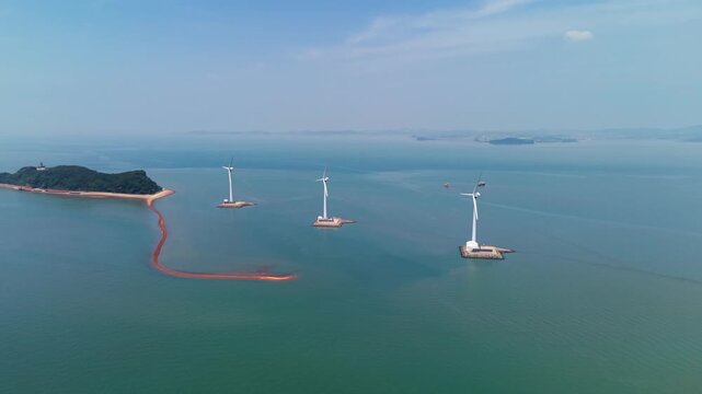 Aerial parallax around three offshore wind turbines of Tando Sea road in emerald ocean water near forested Nue Island with no people