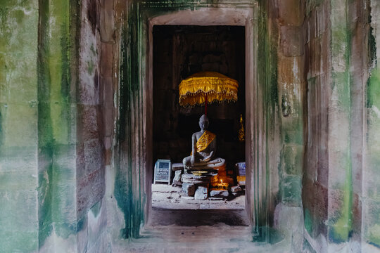 A serene Buddha statue sits within a stone doorway at Bayon Temple, Siem Rep, Cambodia. The ancient temple complex is a UNESCO World Heritage site, attracting visitors and pilgrims.