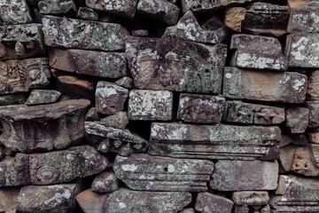 Fototapeta premium Ancient stone carvings of figures and mythical creatures adorn the weathered walls of Bayon Temple, Angkor Wat, Siem Reap, Cambodia, showcasing intricate Khmer artistry.