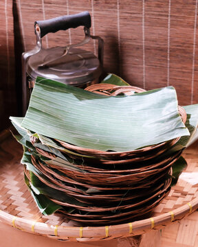 Tumpukan nampan anyaman bambu yang dilapisi daun pisang, disiapkan untuk menyajikan makanan tradisional Indonesia.