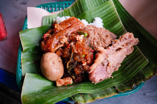 Gudeg rice dish is a traditional food from Yogyakarta, Indonesia, served on banana leaves with braised egg, chicken opor, krecek, and jackfruit vegetables.