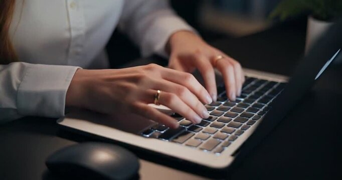 Close-up shot of woman's hands typing on laptop keyboard