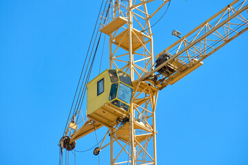 Naklejka premium A tall construction crane is seen working under a clear blue sky