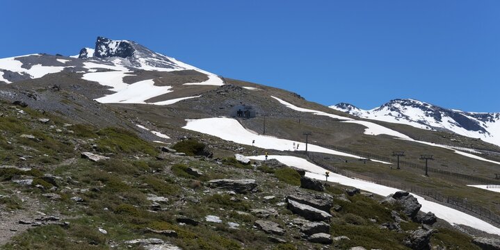 Snow-covered mountain with cable car supports and ski slopes under a blue sky, Pico del Veleta, Veleta peak, Hoya de la Mora, Maurin basin, G&uuml;&eacute;jar Sierra, G&uuml;ejar, Sierra Nevada, Andalusia, Spain