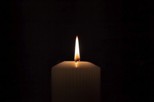 Flame, single candle burning in the darkness, symbol of hope