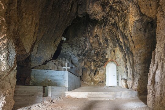 Interior view of a rocky cave with a tomb and a cross, a white niche visible, Church of Mary the Fountain of Life, Zoodochos Pigi, Rock Church, Kefalari, Argolis, Peloponnese, Greece