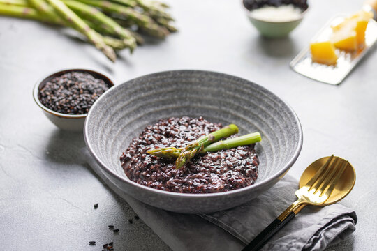 Black rice risotto with asparagus in ceramic bowl. Italian Cuisine.
