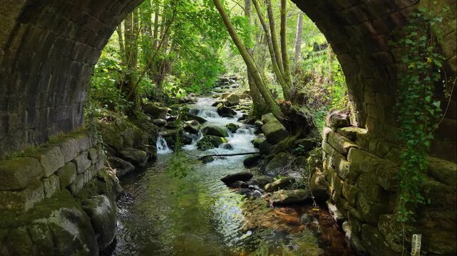 Rushing Streams Of The Vaos River Over Historical Stone Bridge Of Lumeares In Galicia, Spain. Aerial Pullback Shot