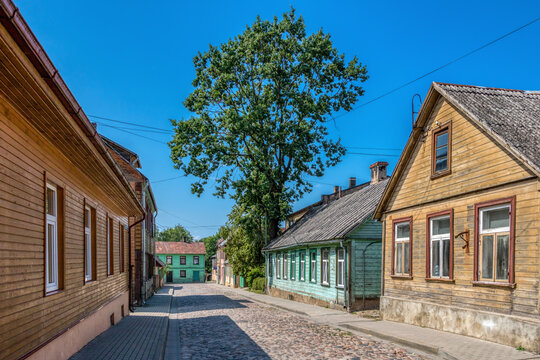 Historic wooden houses along a cobblestone street in the old town of Tukums Latvia on a sunny day