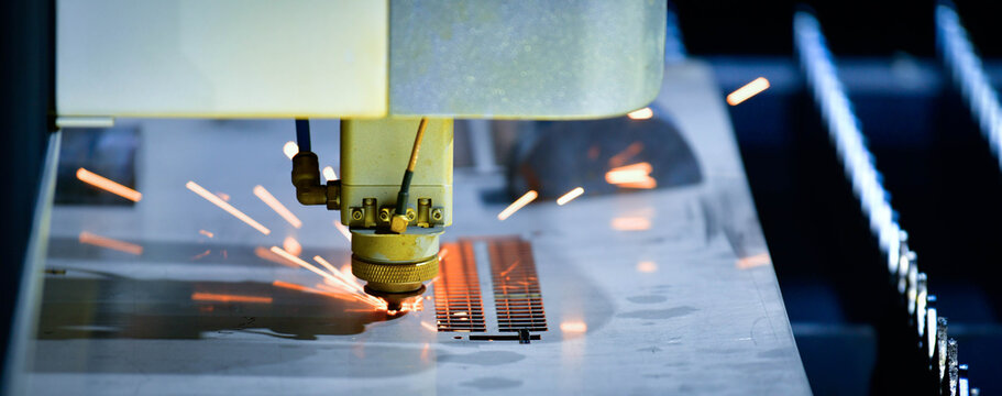 Industrial CNC laser cutter processing steel plate in metalworking factory.