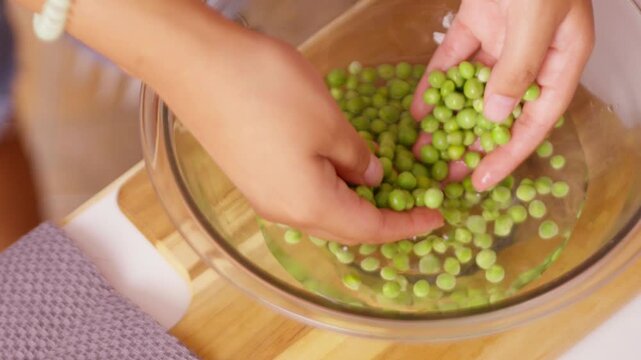 Woman's hands washing fresh green peas