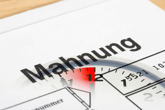 Ein Mahnung und eine Uhr 5 vor 12 als Symbol f&uuml;r den Zeitdruck und Stre&szlig; wegen unbezahlter Rechnungen	