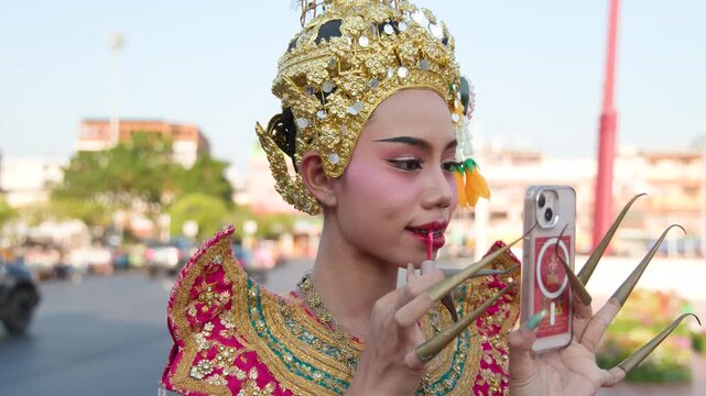 Thai Classical Dancer Applying Lipstick While Looking into a Smartphone Screen