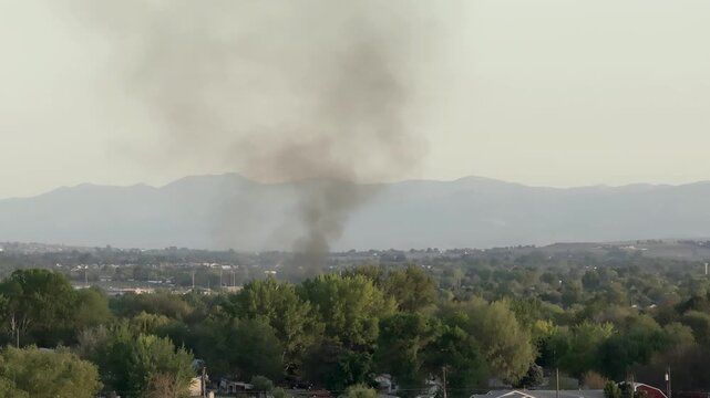 Thick smoke billows from unseen source over residential area