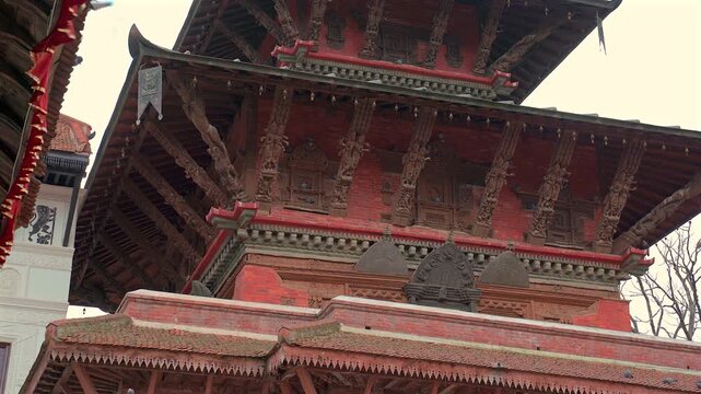 A static low-angle close-up shot focusing on the exquisite historical wooden struts and detailed carvings of an ancient Newar pagoda temple in Nepal
