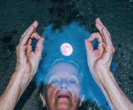 Senior woman hands in shuni mudra gesture over a water puddle with full moon reflection for spiritual wellness, meditation practice and mindfulness background