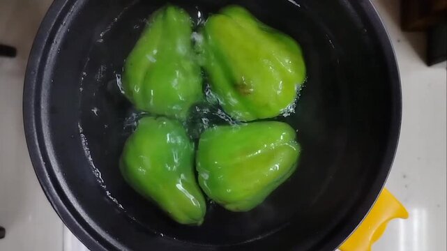 Video of a chayote being cooked until it boils in an electric pan
