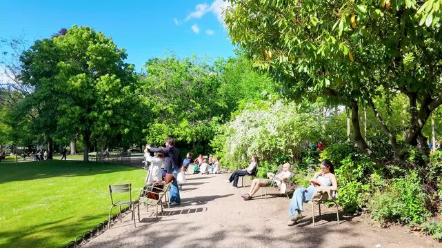Tourists Relaxing and Reading in a Sunny Public Park in Paris