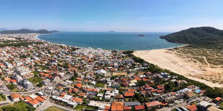 Panoramic aerial view of Ingleses beach residential district and urban development with massive sand dunes and calm ocean bay in Florianopolis, Brazil