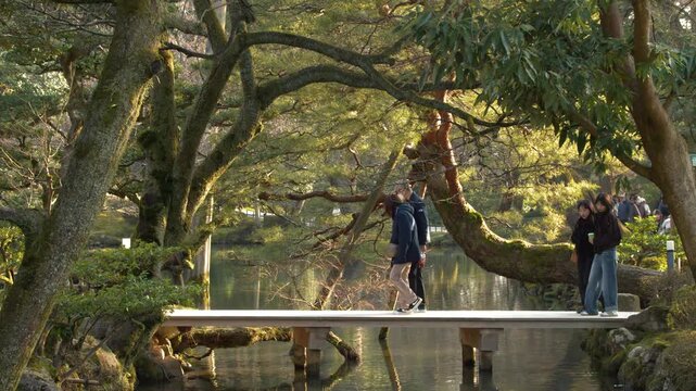 Tourists Walking Across a Wooden Bridge in Kenrokuen Garden Kanazawa