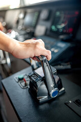Captain hand holding throttle control or engine control lever on boat dashboard with GPS navigation and marine radar in wheelhouse or ship bridge. Speed adjustment instrument for seafaring technology © zephyr_p