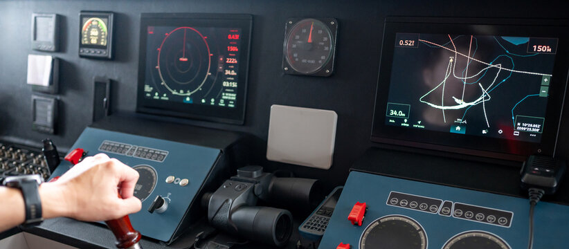 Captain hand holding steering wheel while controlling dashboard. GPS navigation map and marine radar monitor for modern boating technology. Nautical vessel control panel in wheelhouse or ship bridge