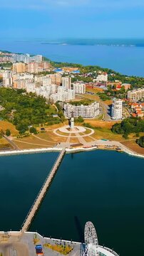 Vertical video. Cheboksary, Russia. Mother Patroness Monument, a 46-meter copper-clad figure with outstretched arms overlooking Cheboksary Bay, aerial panoramic view over the Volga River waterfront. 