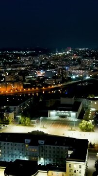 Vertical video. Oryol, Russia. Lenin Square and the House of Soviets, aerial night view over the illuminated city center with the Oka River embankment stretching into the distance. Drone footage. Ric