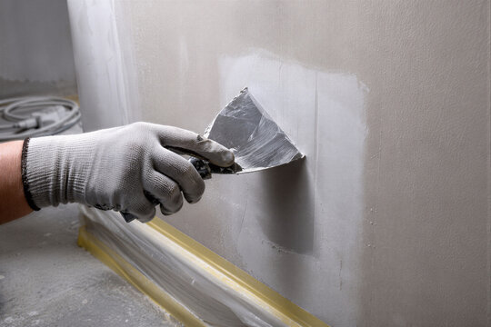 Applying Wall Filler with Putty Knife as Drywall Repair and Home Renovation Concept
