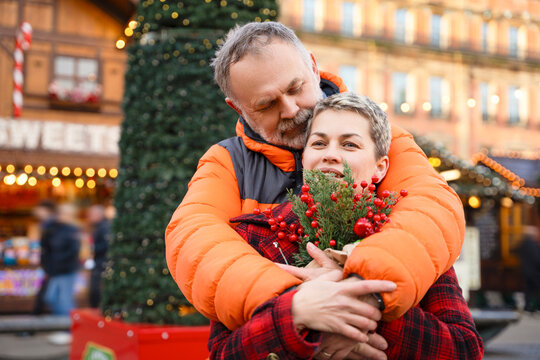 Couple enjoys holiday market while celebrating winter season in a festive town square