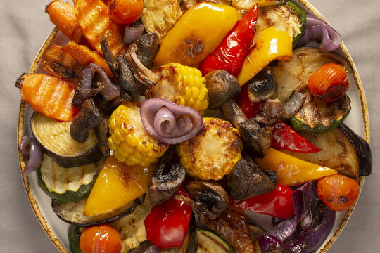 Crisp ovenroasted vegetable medley on plate with zucchini, peppers, tomatoes and corn, bright caramelization and savory glaze,