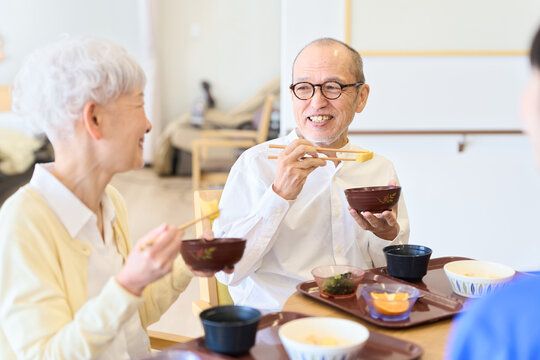 介護施設で話をしながら食事をするシニア