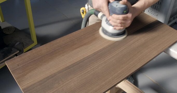 Carpenter working timber with orbital sander
