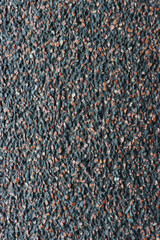 Fototapeta premium A black and brown stone wall with a lot of small rocks on it