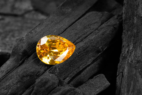 yellow gemstone on black coal background, close up shot