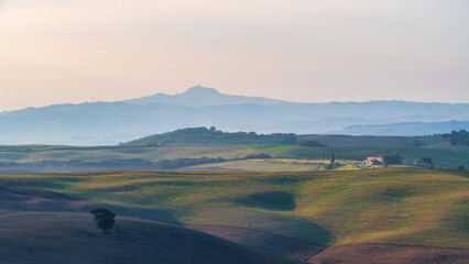 Obraz premium Beautiful sunrise landscape of Tuscany rolling hills with morning fog and distant mountains, Italy