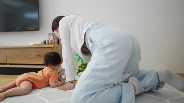 Mother and child play together on a rug. They engage with a colorful toy tower. Child looks up at mother with curiosity. Scene captures tender, playful family interaction