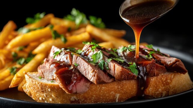 Open-faced roast beef sandwich with gravy being poured and french fries