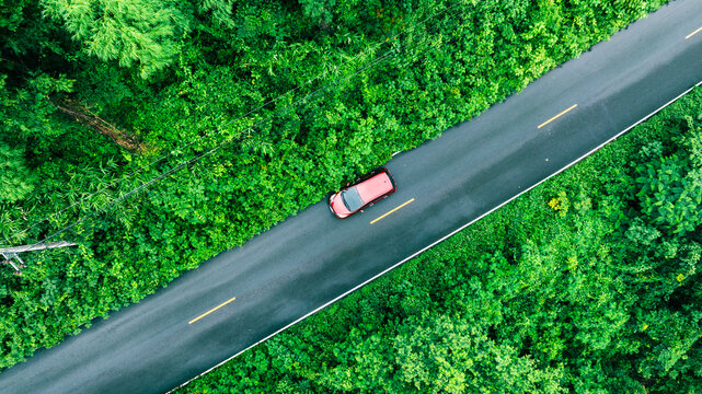 Tropical aerial forest background with asphalt road and isolated car, perfect for electric vehicle promotion, climate awareness campaigns and ESG corporate communication.